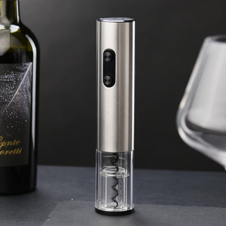 Electric wine opener on a dark surface with a bottle and glass in the background