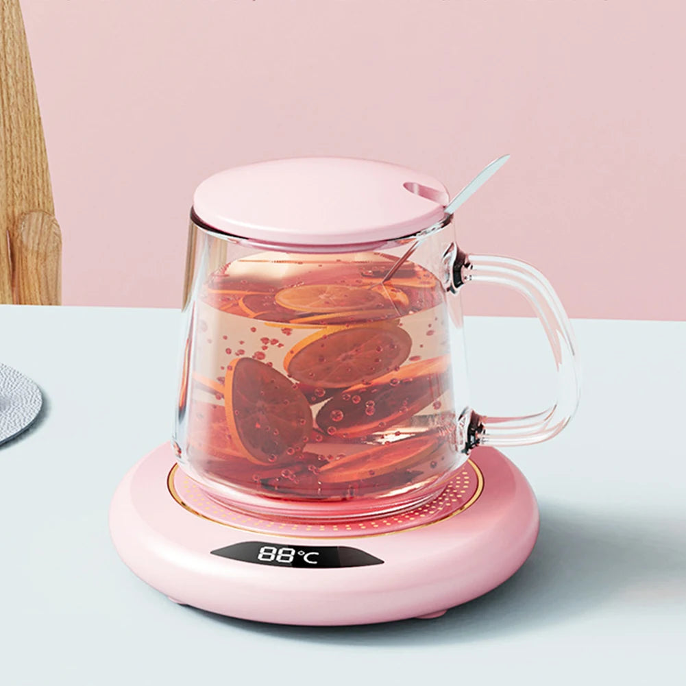 Pink electric tea maker with a clear glass container on a light blue surface.