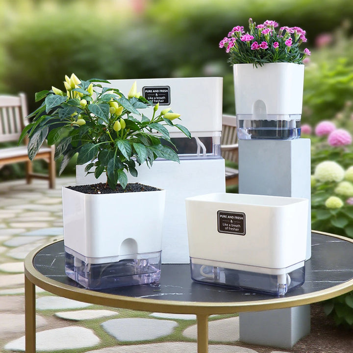 Set of self-watering planters with plants on a table outdoors